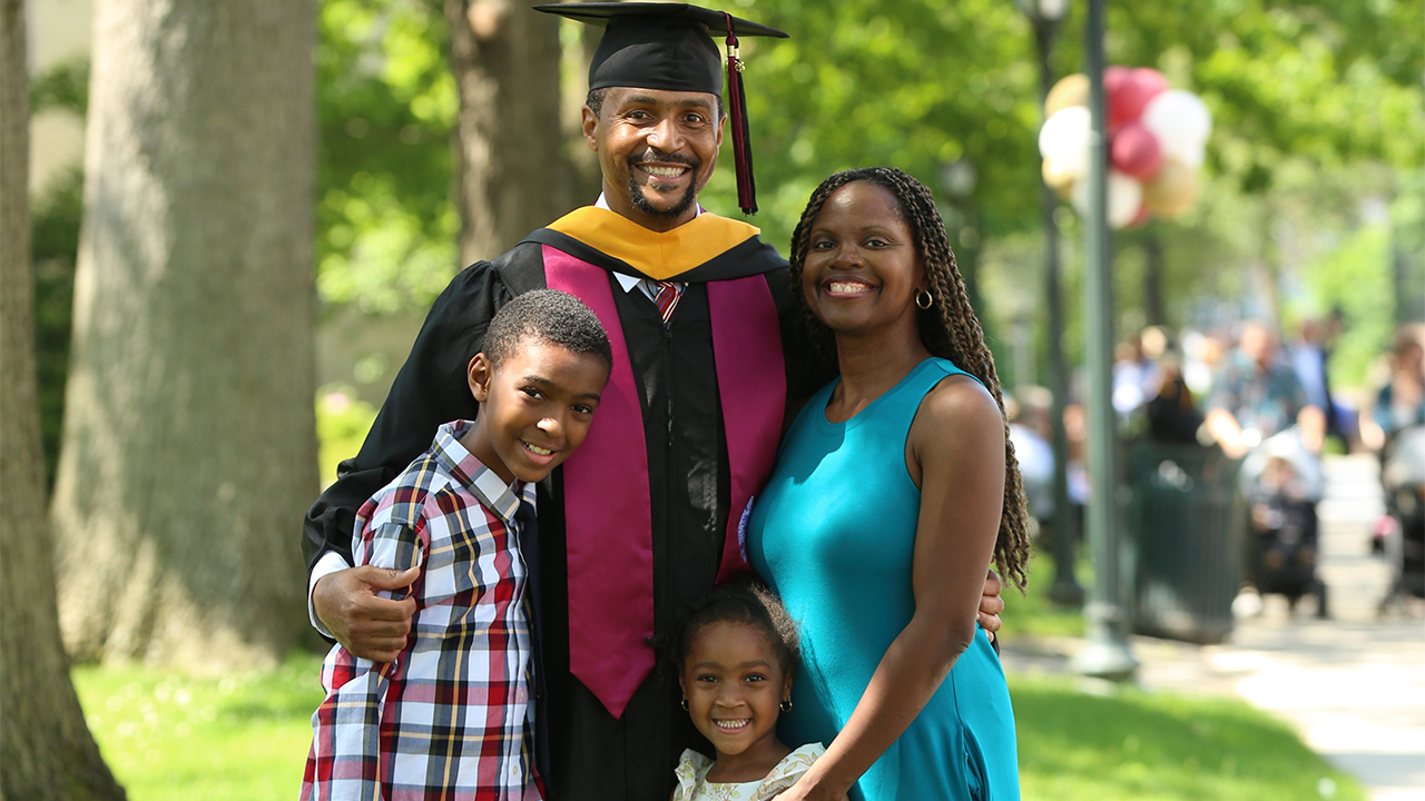 PCS grad Bryant Wingfield with his wife and two kids with trees behind them