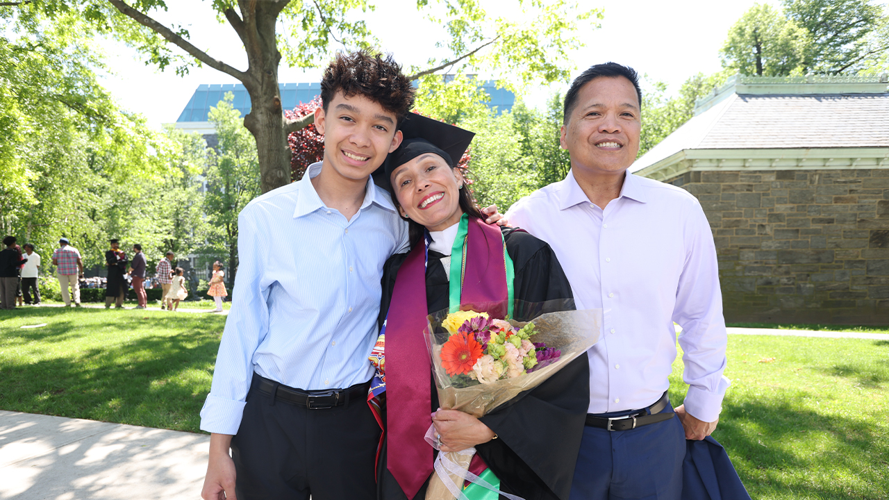 PCS grad Eliane Victoria with her husband and son with leafy background