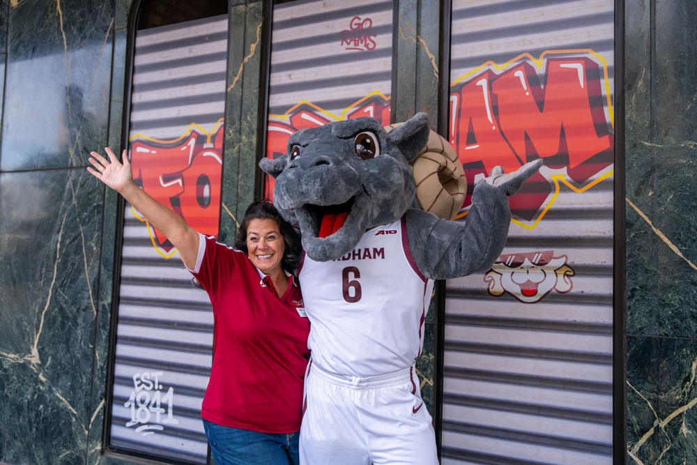 A Maroon Mart employee and Ramses pose in front of Fordham grafitti