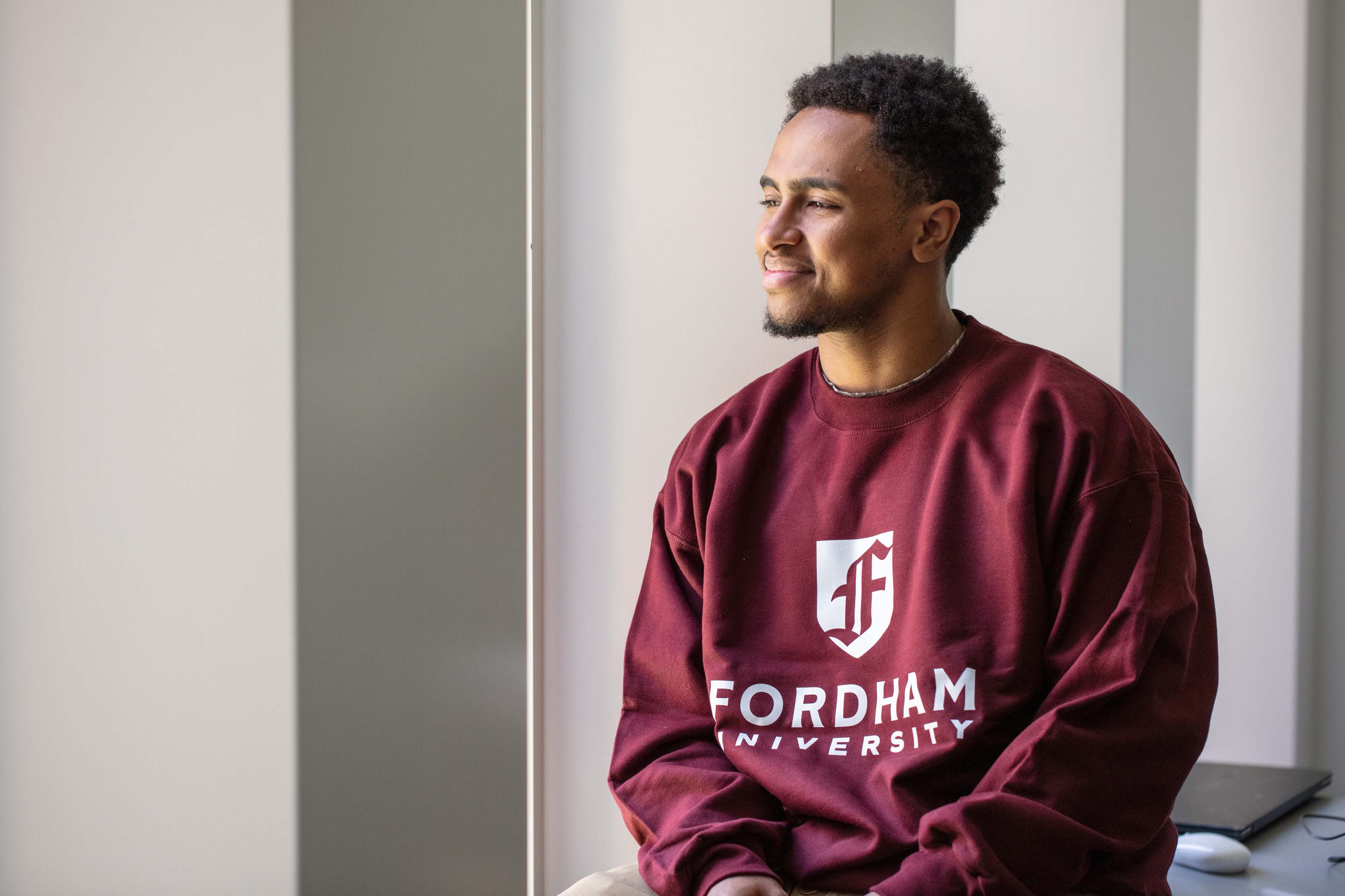 student smiling sitting on desk in classroom