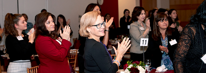 Women clapping and standing at the women's philanthropy summit