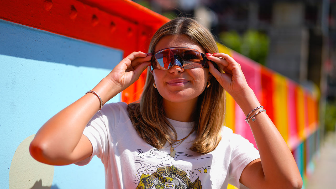 A female student posing with a pair of sports sunglasses