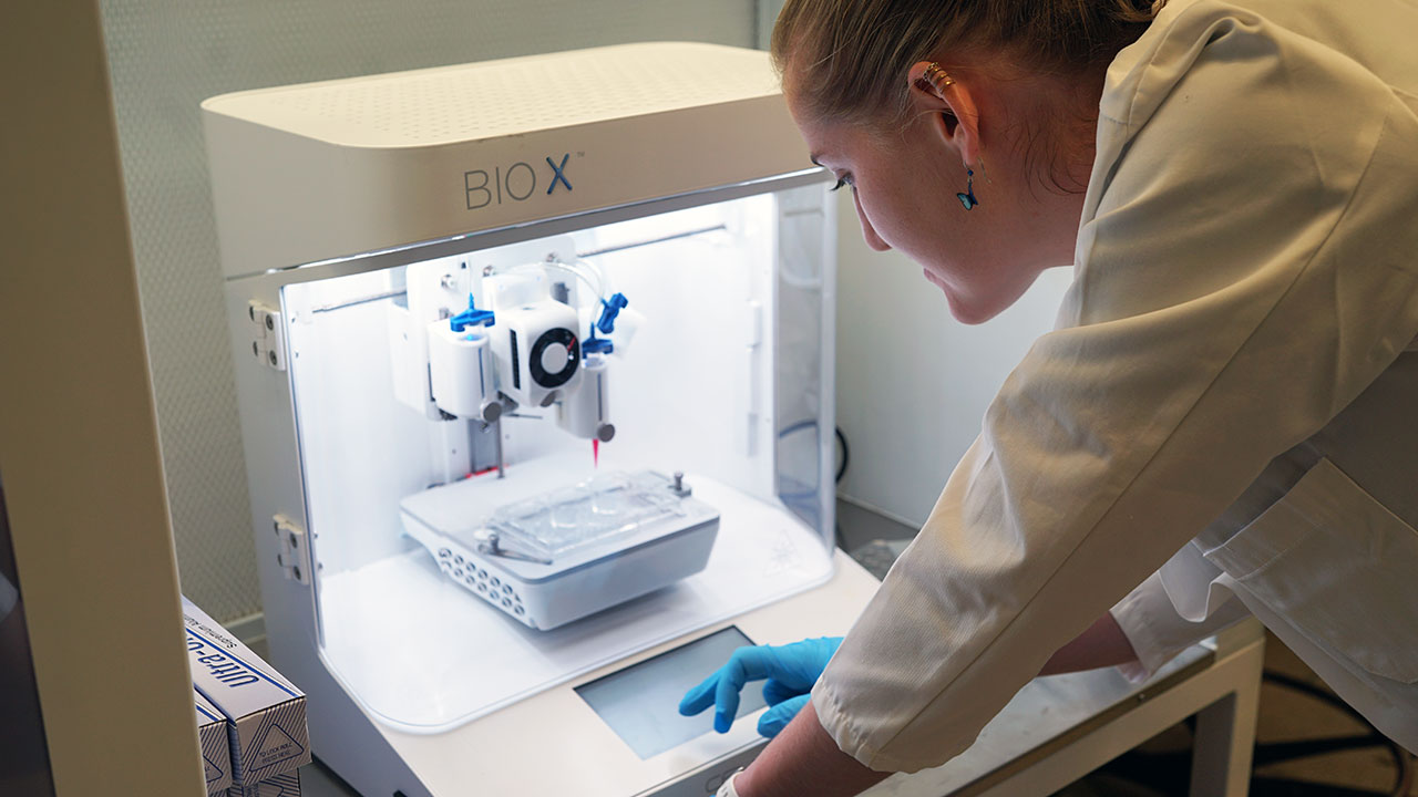 A student uses a 3D printer inside a lab at Fordham.