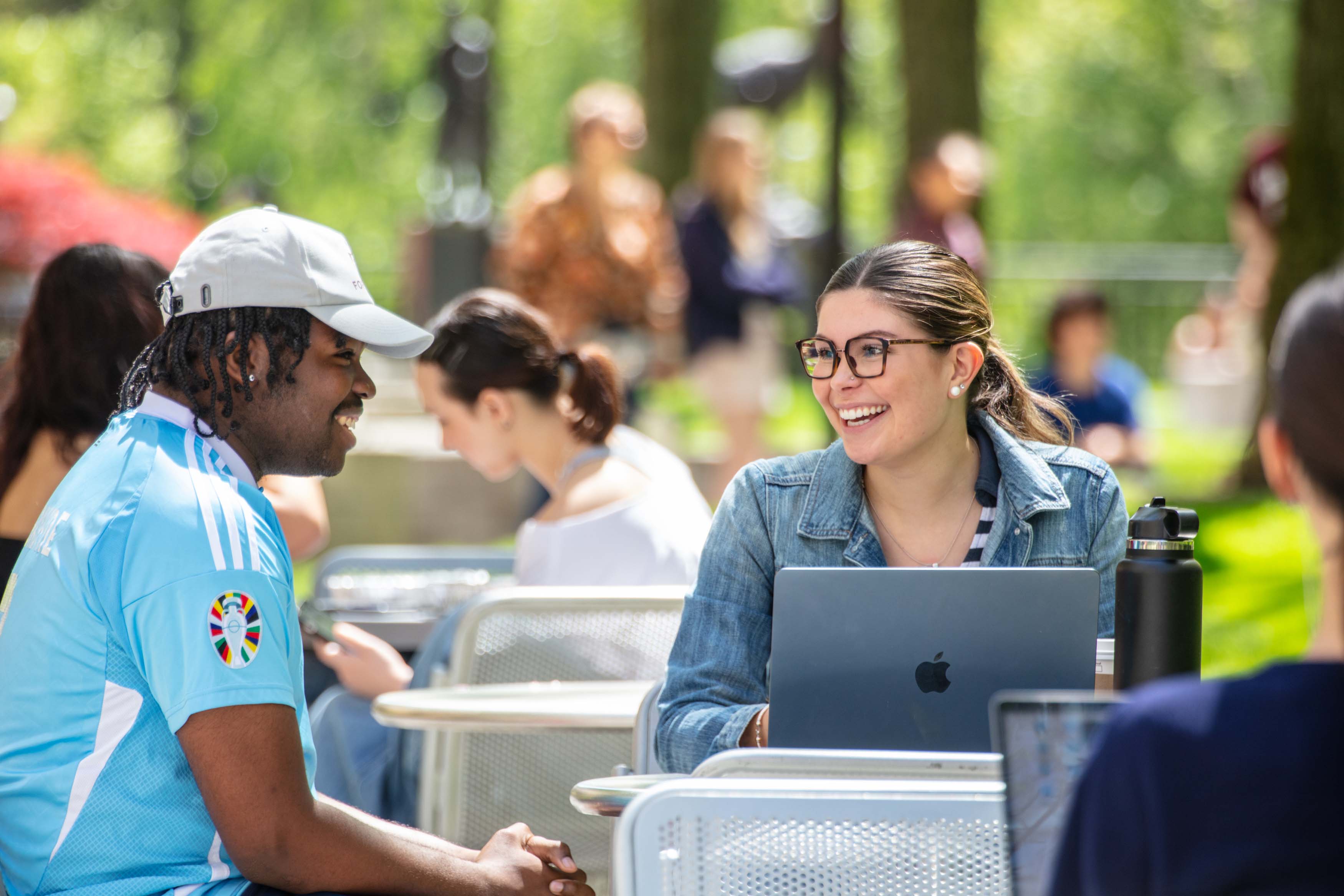 students sitting at table talking with laptop