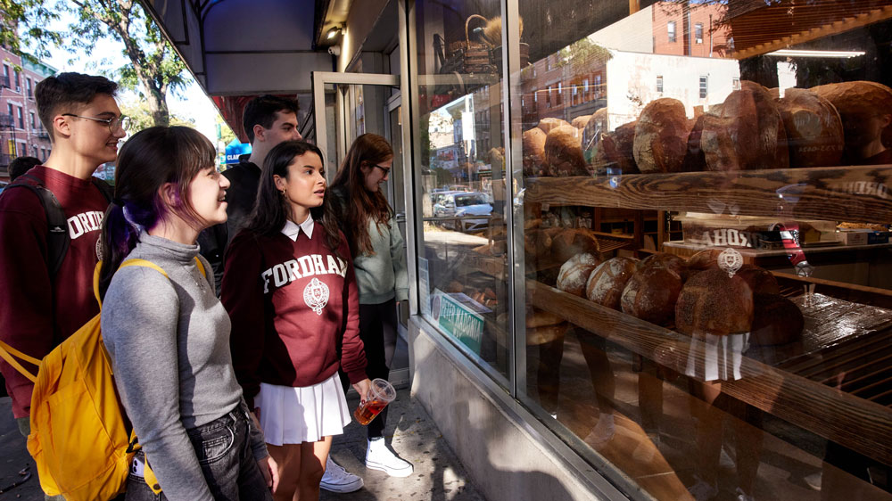 Students look at bread in the window of an Italian bakery on Arthur Avenue