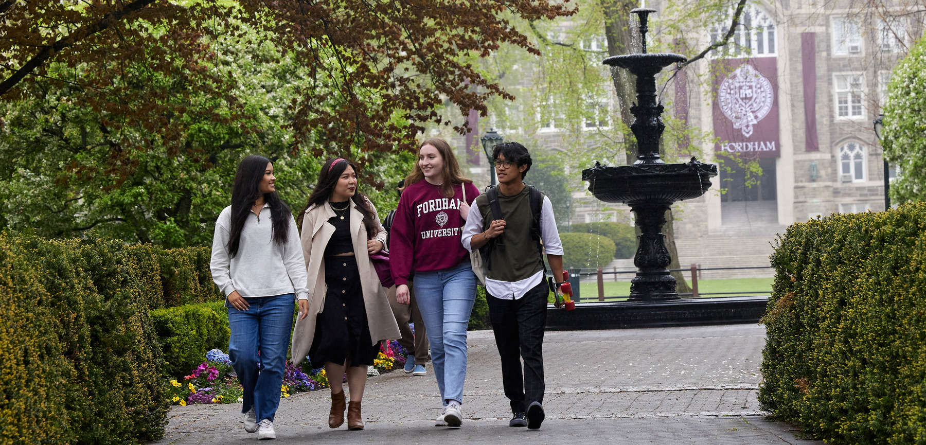 Four students walking and talking on the Rose Hill campus near the fountain