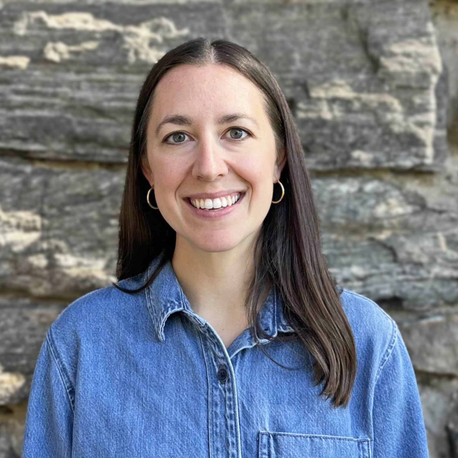 Katie Turo smiling in front of a rock wall background