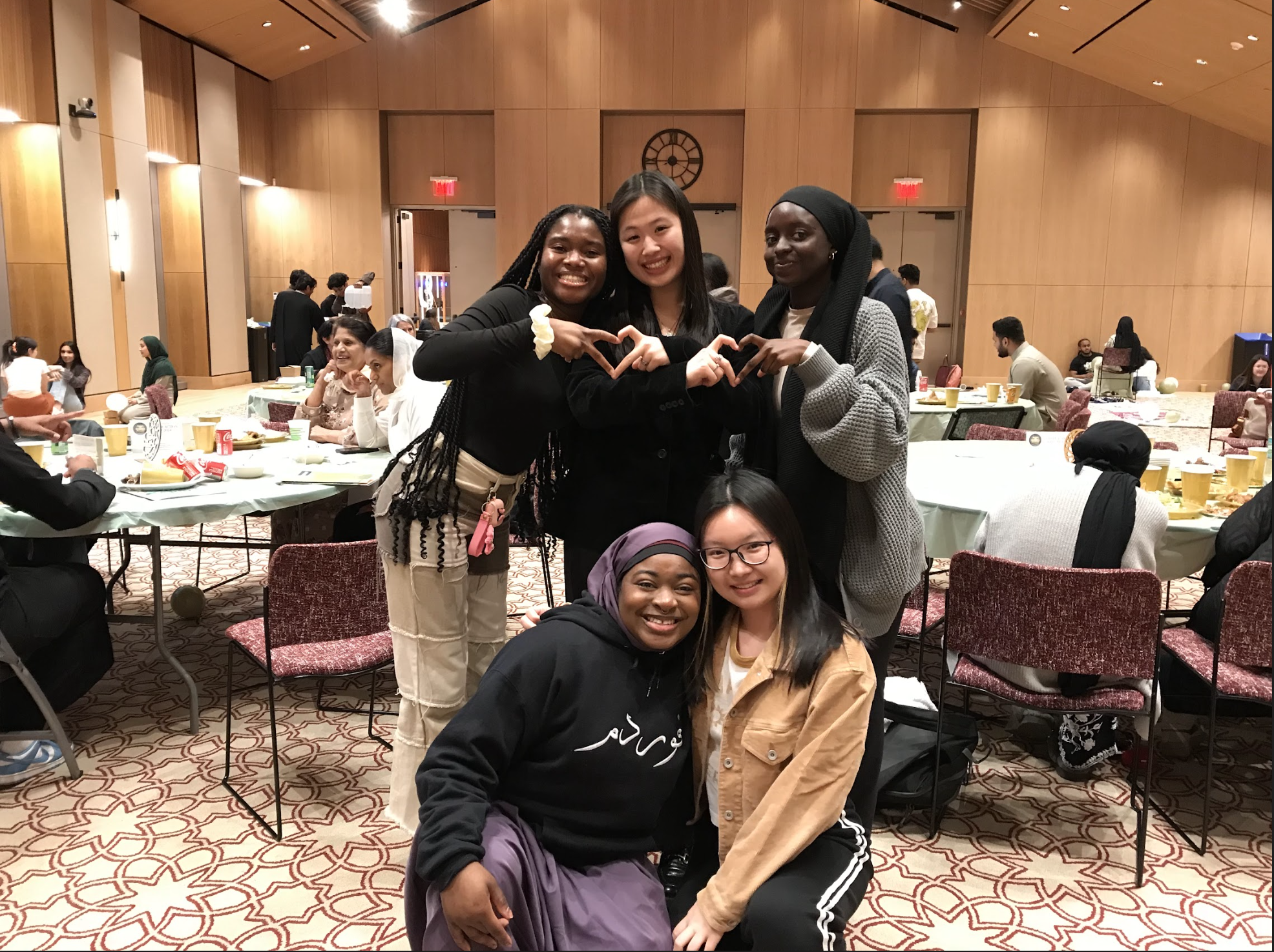 Group of 5 women smiling and making a heart with their hand