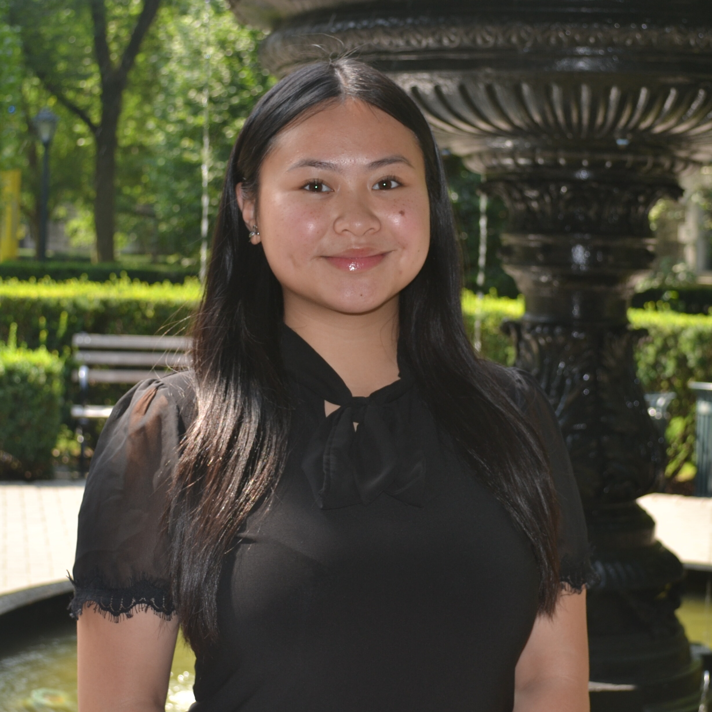 Dana smiling in front of a water fountain