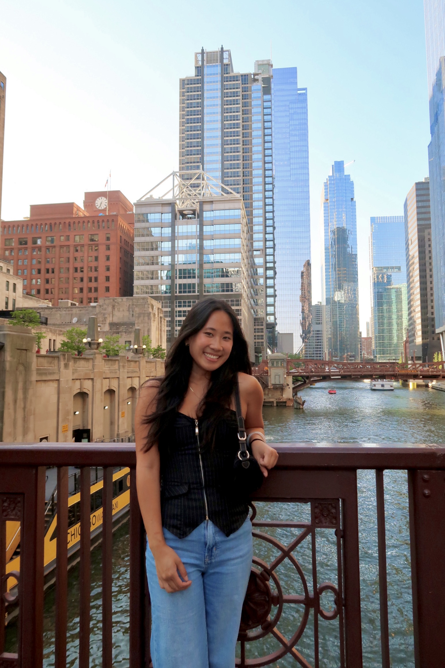 Kaila standing on a bridge over a river with a skyline in the background