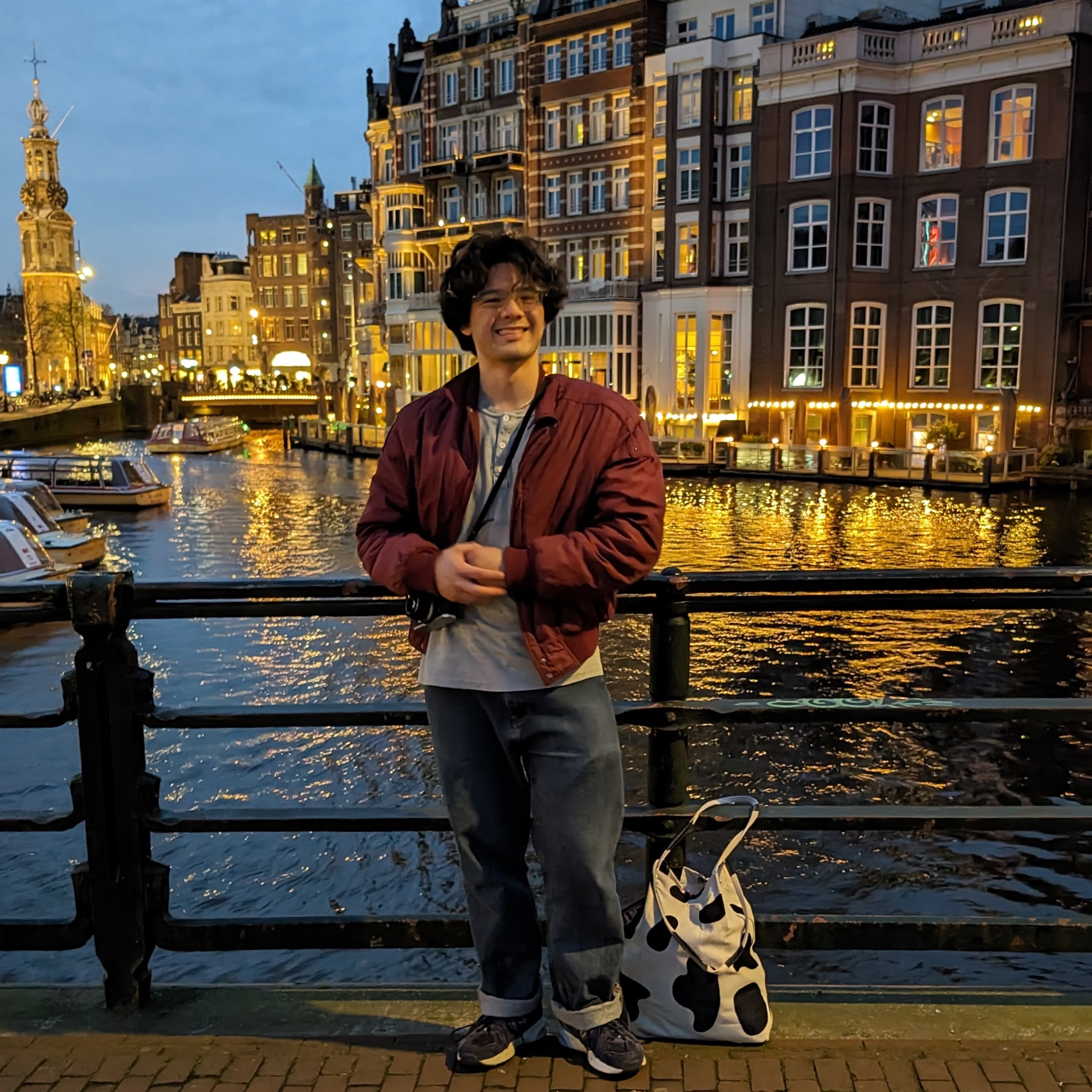 Student standing in front of a canal and buildings at night