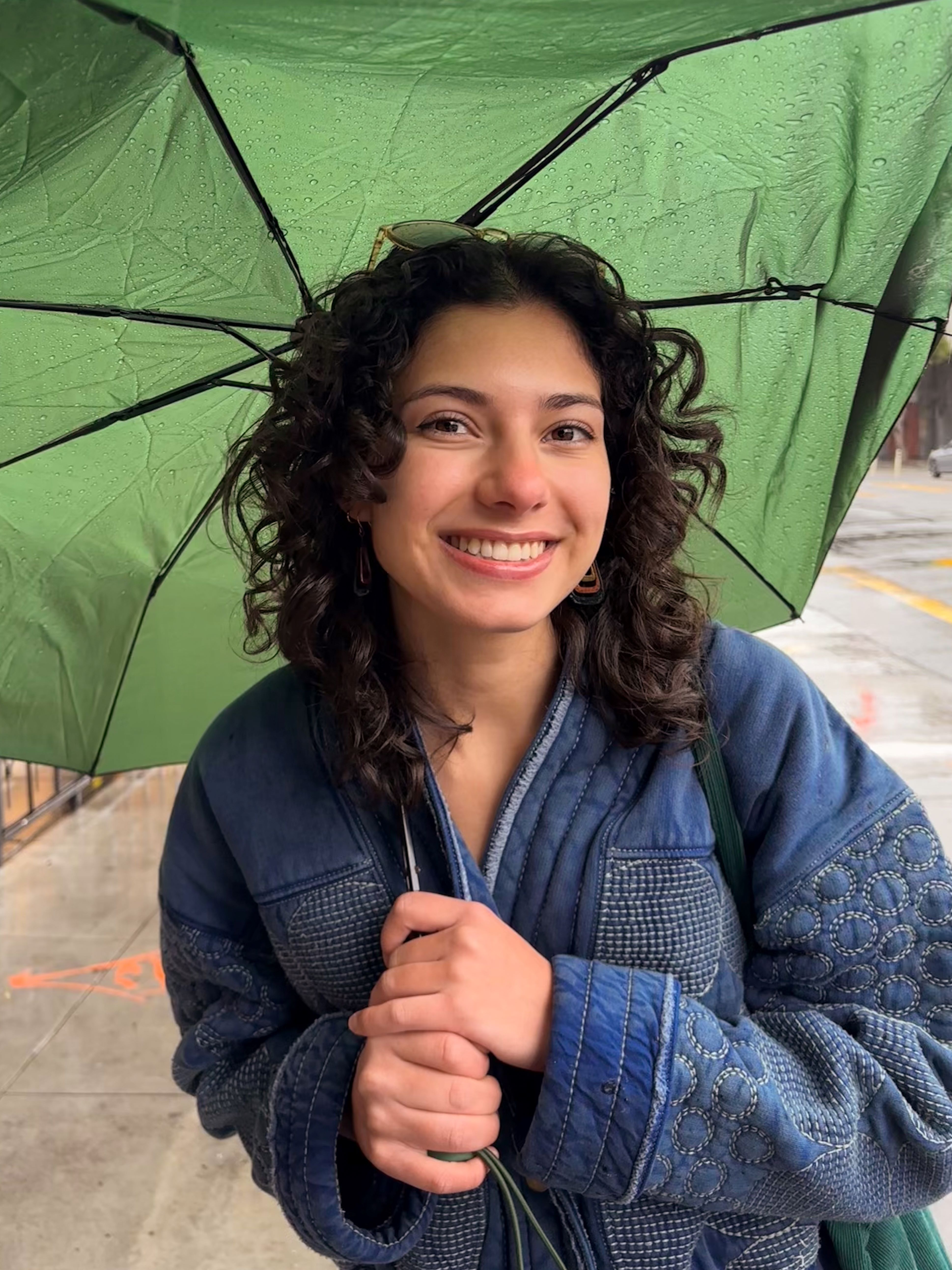 A student standing under a green umbrella
