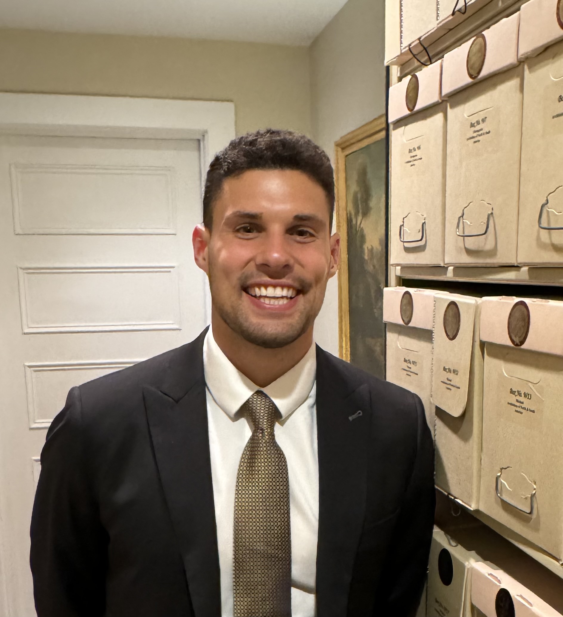 Young man in a suit with brown hair and a gold tie.