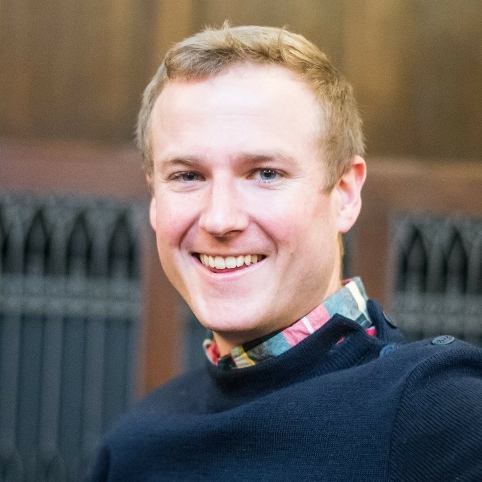 A headshot of Jason Steidl Jack, a 2018 PhD graduate of the Theology Department at Fordham. Steidl Jack is wearing a navy crewneck sweater with the collar of a plaid collared shirt above the sweater collar.