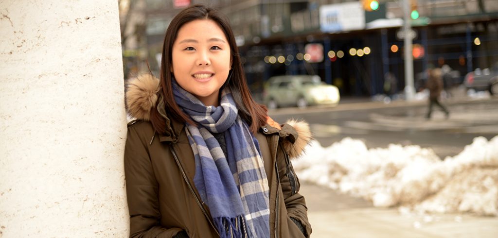 young woman in green jacket and blue scarf.