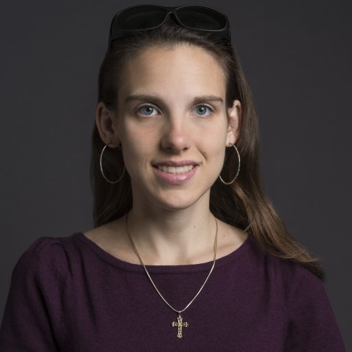 Young woman in purple shirt with sunglasses on top of head.