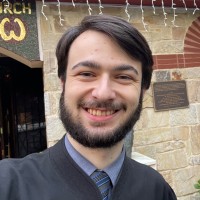 young man with black hair and beard with shirt and tie.