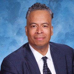 Amilcar DaSilva sitting in front of blue background