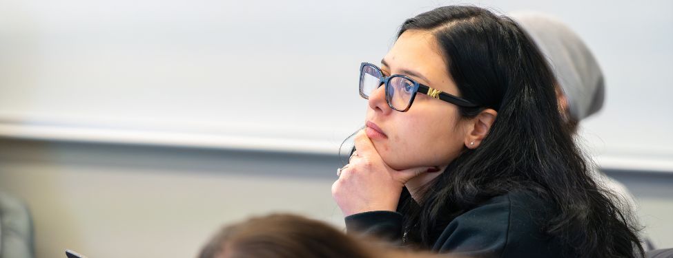 A Fordham MSW advanced standing student sits in a classroom listening intently to the professor.