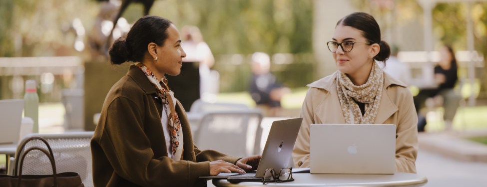 two students sitting at a table in the lincoln center campus courtyard