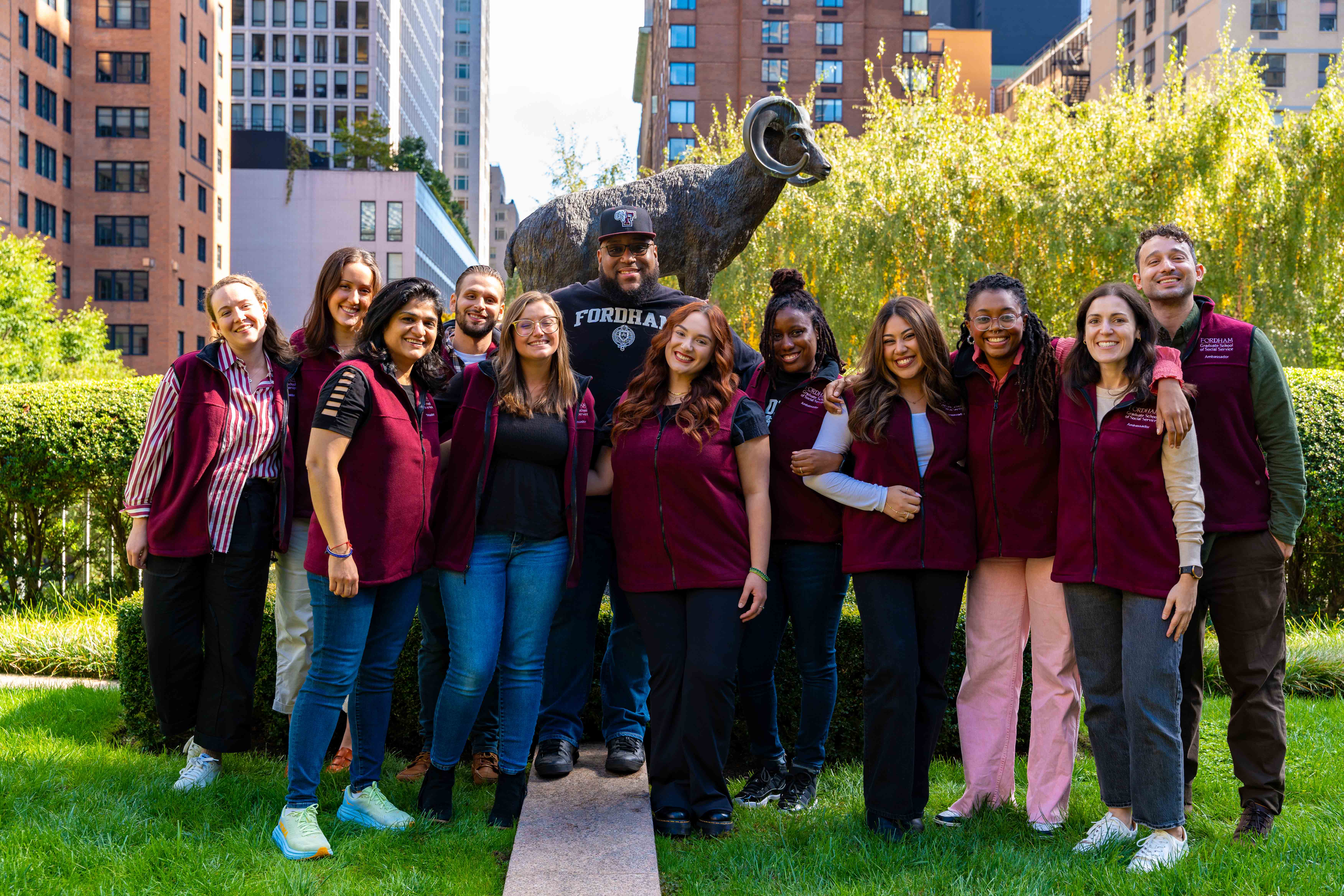 the fall 2024 student ambassadors stand in the lincoln center courtyard smiling. they're in front of the ram statue.