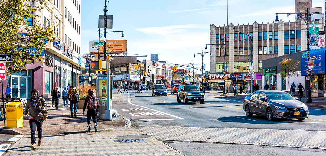 Pedestrians on sidewalk next to road in the Bronx